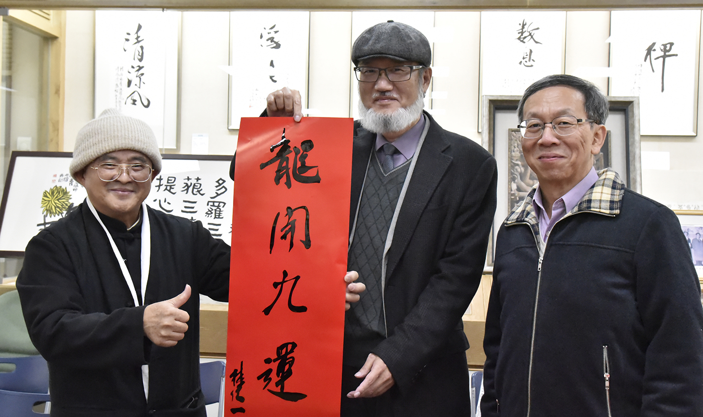林從一校長（中）於春聯活動開筆書寫「龍開九運」，與佛教藝術學系吳大仁老師（左）、簡江儒教務長合影。