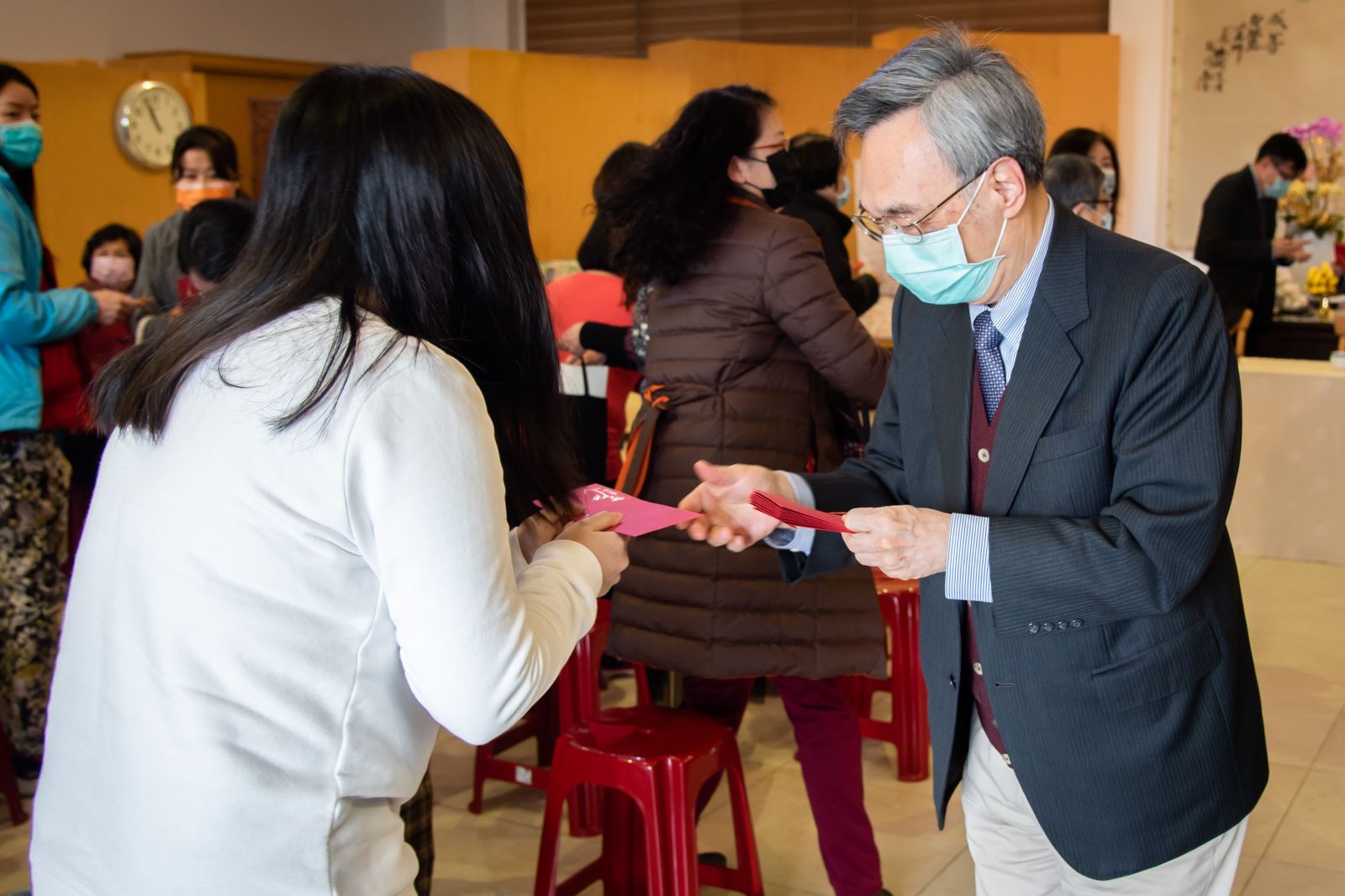 李復甸董事（右）代董事長悟觀法師發送教職同仁新年祝福紅包，感謝同仁努力。