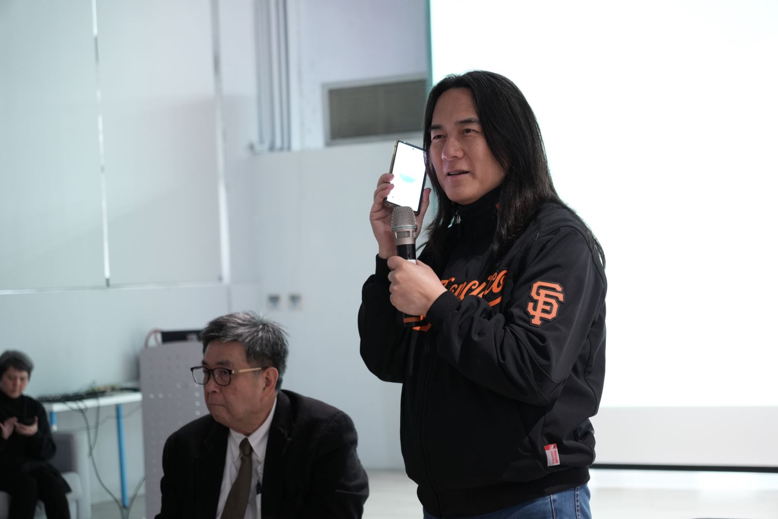 智慧生活科技學系副教授翟本喬（右）示範AI科技在日常的應用。